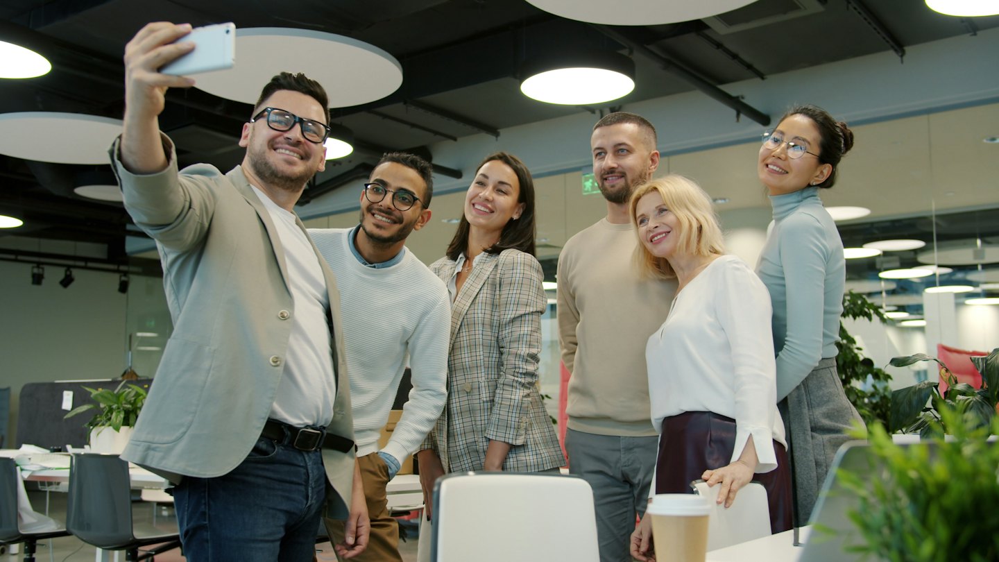 Un team si scatta un selfie in un ufficio moderno e luminoso.