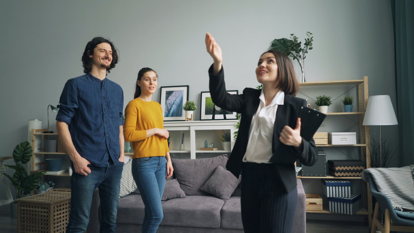 Agente immobiliare mostra un soggiorno moderno a una coppia.